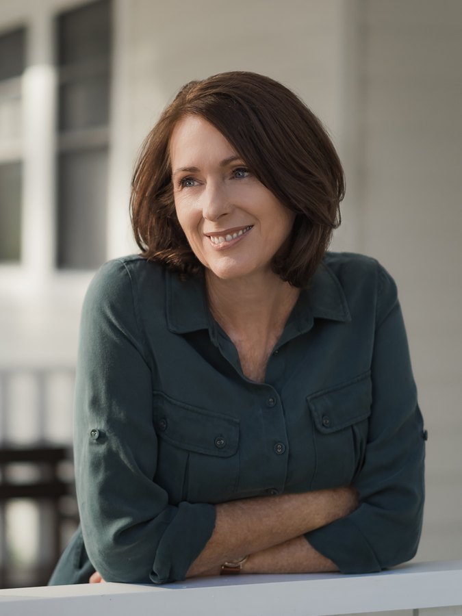 Cindy McGarvie leaning on a white verandah rail, smiling